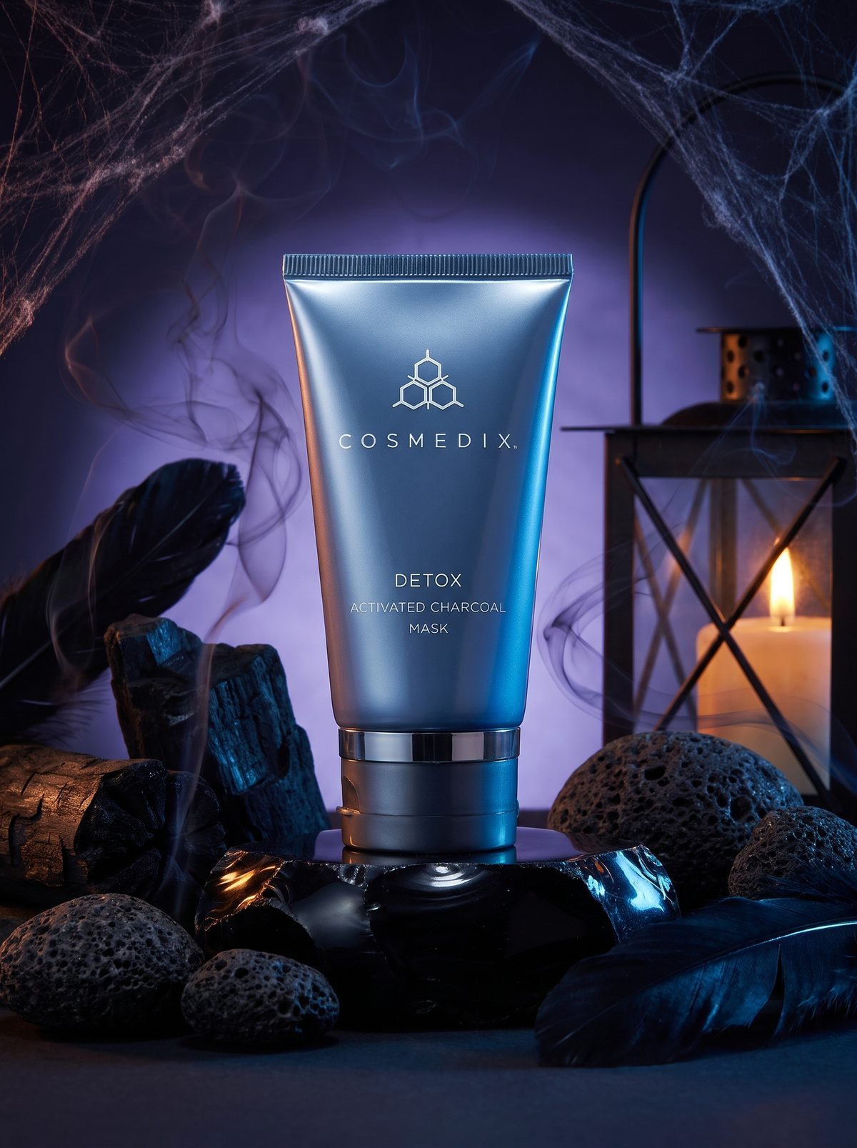 Cosmedix Detox Activated Charcoal Mask na czarnym kamieniu obok latarni i węgla